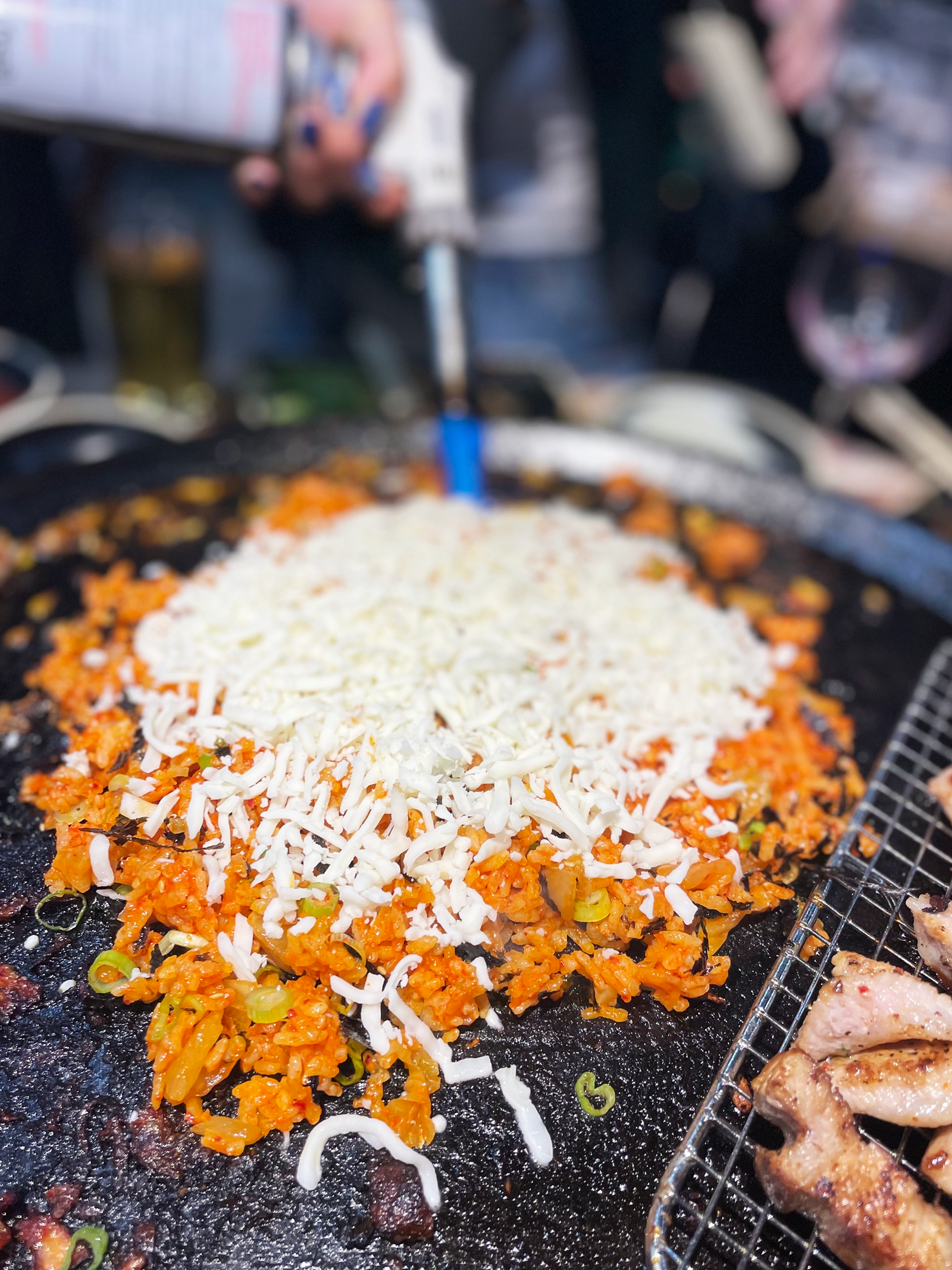 Samgyeopsal with bean sprouts and kimchi on the cast-iron lid at Pigya