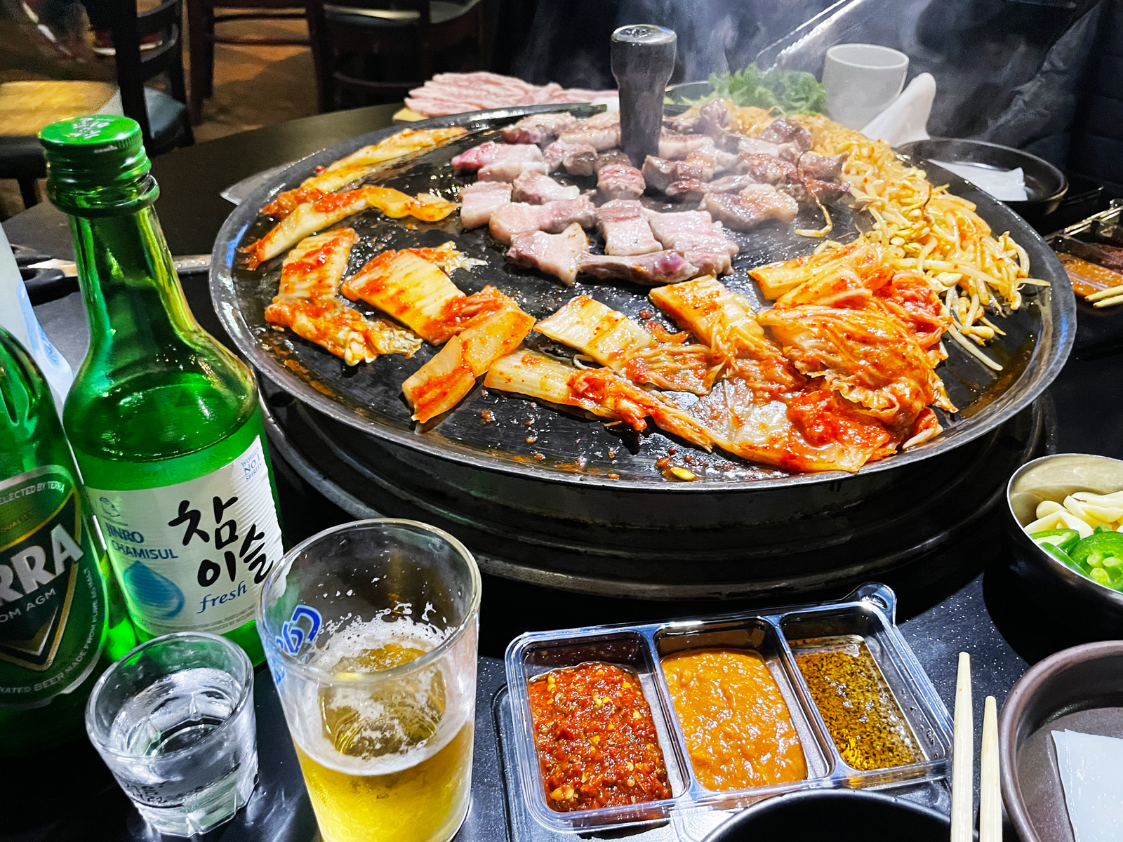 A table spread with meat , banchan, soju and beer at Pigya Koreantown , LA