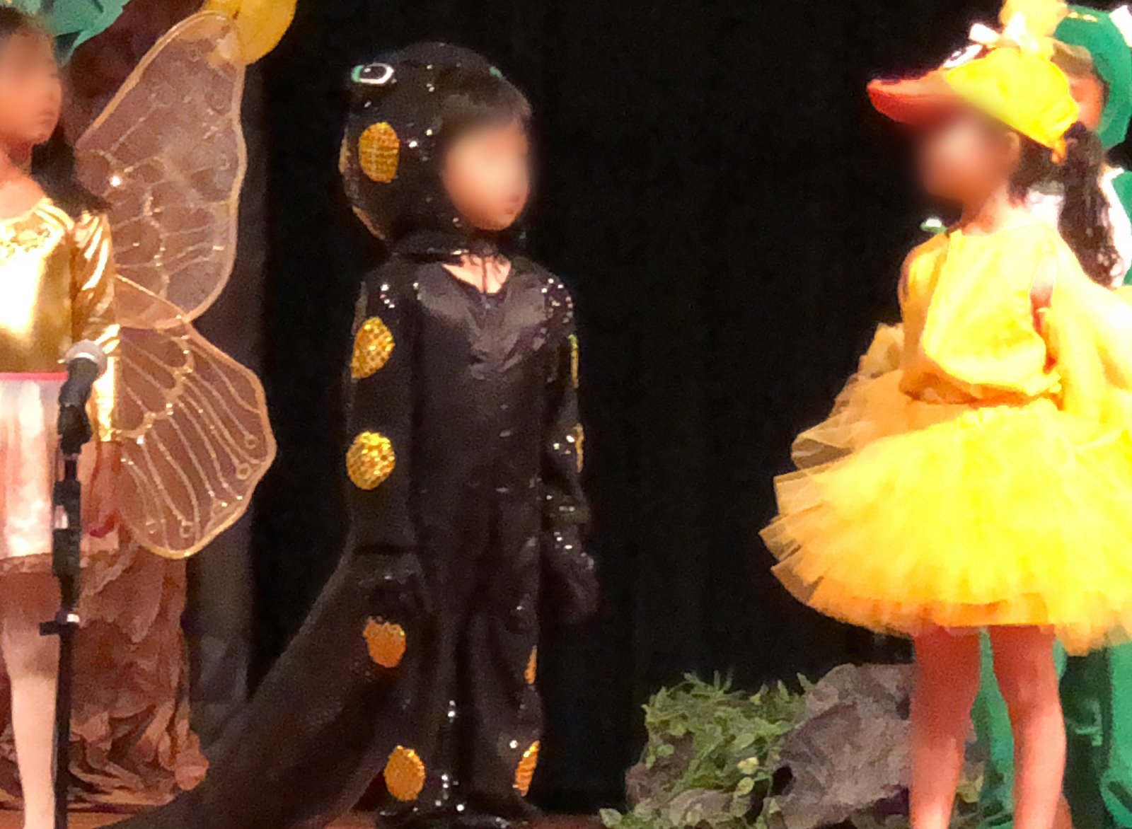 Child in handmade spotted salamander costume on stage with other children in a school playsalamander costume for kids
