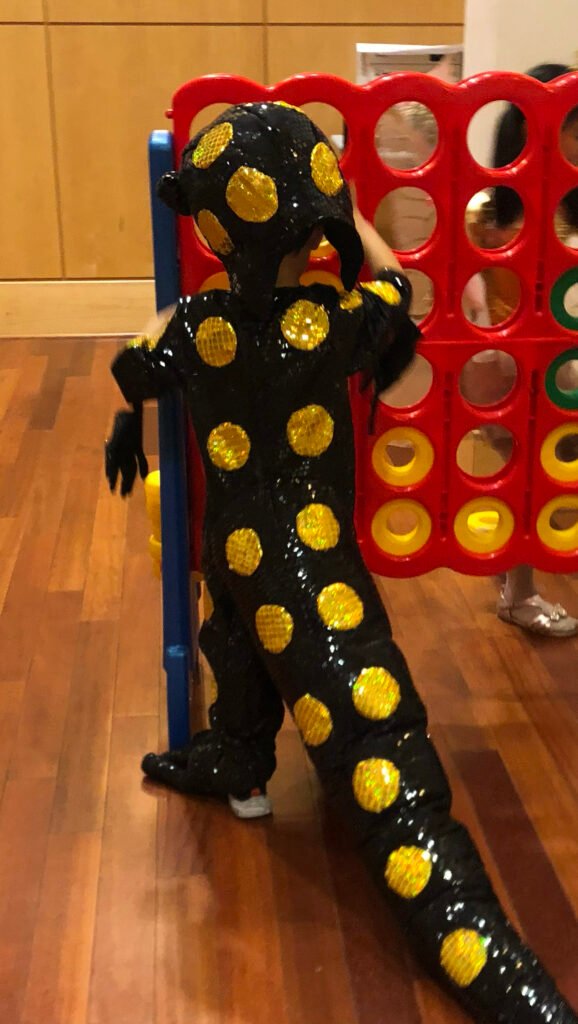 Back view of handmade spotted salamander costume showing rows of gold spots and long tail