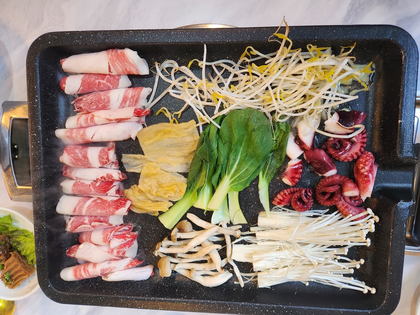 A platter of Korean beef and octopus prepared for grilling at a restaurant in Jeonju