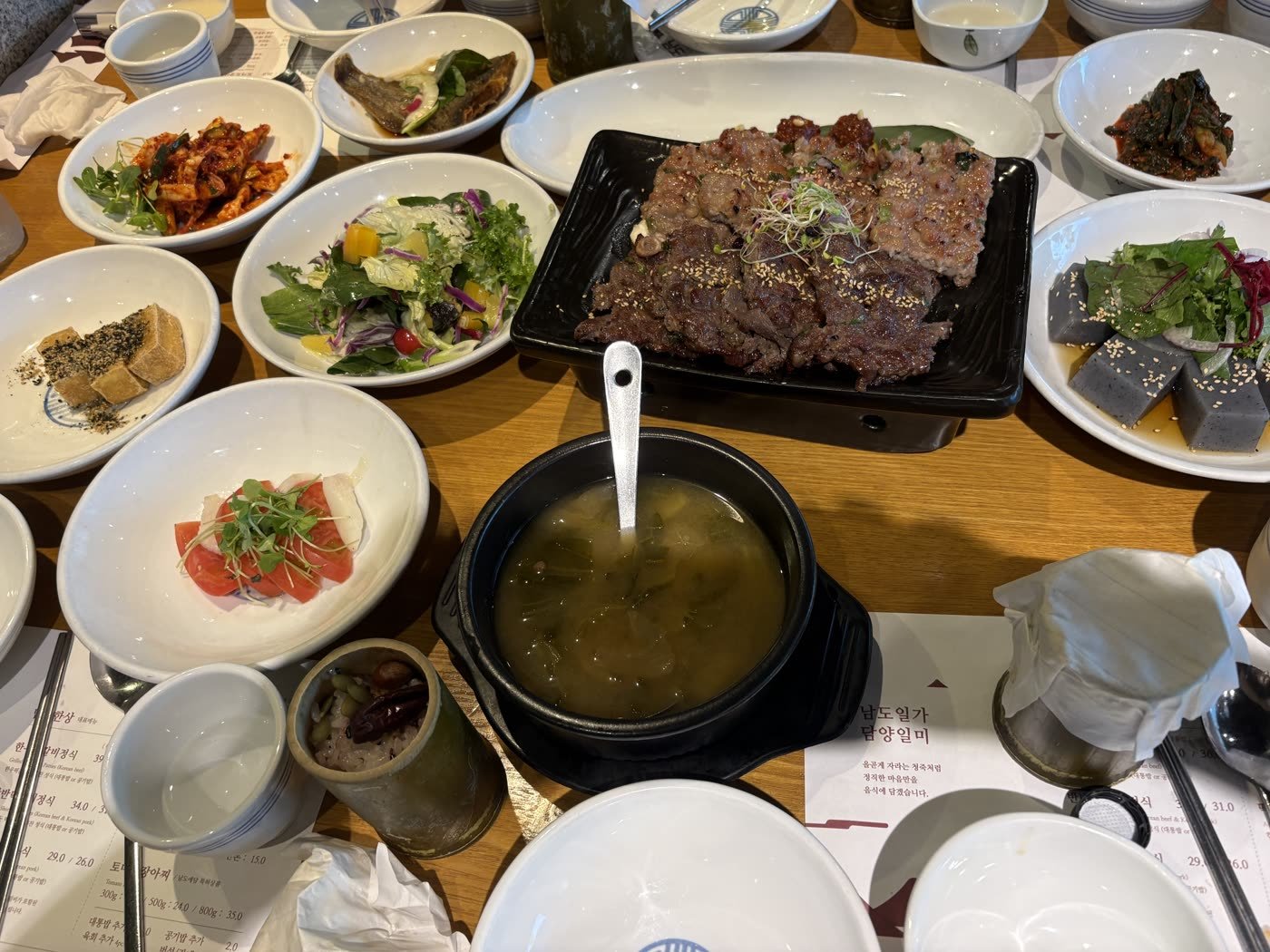 A Korean tteokgalbi set meal with many side dishes on a wooden table in Damyang