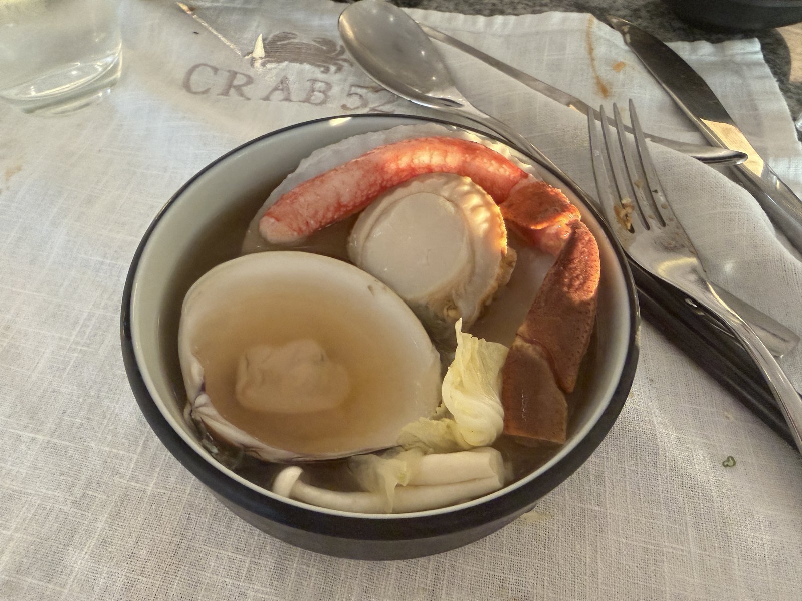 Clear seafood shabu broth with a giant scallop, abalone and a snow crab leg at Crab 52 Seoul
