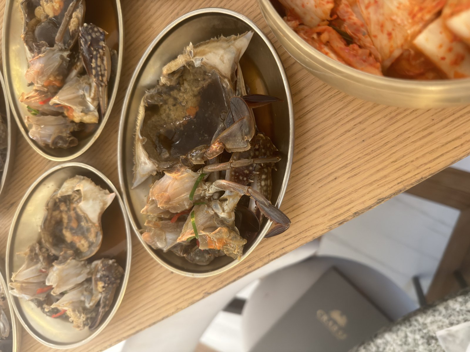 Soy-marinated raw crab halves served on a wooden board at Crab 52 Seoul