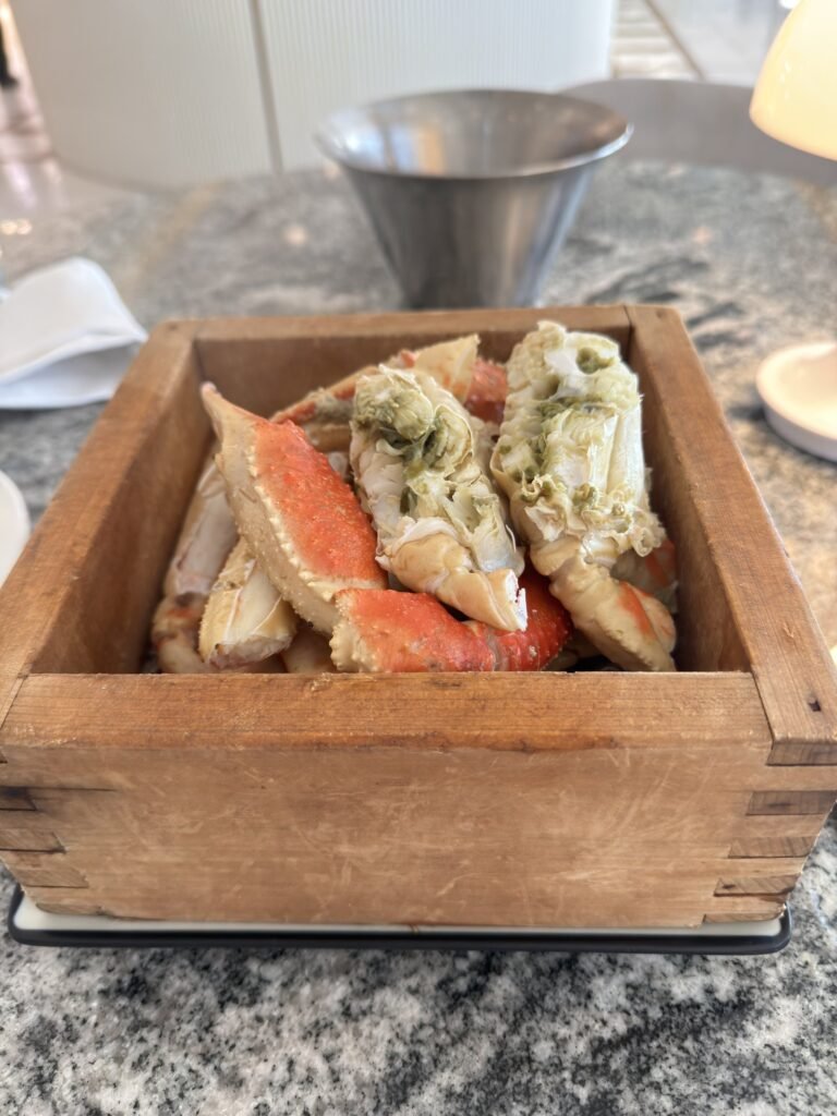Steamed snow crab legs served in a shallow wooden crate at Crab 52 Seoul
