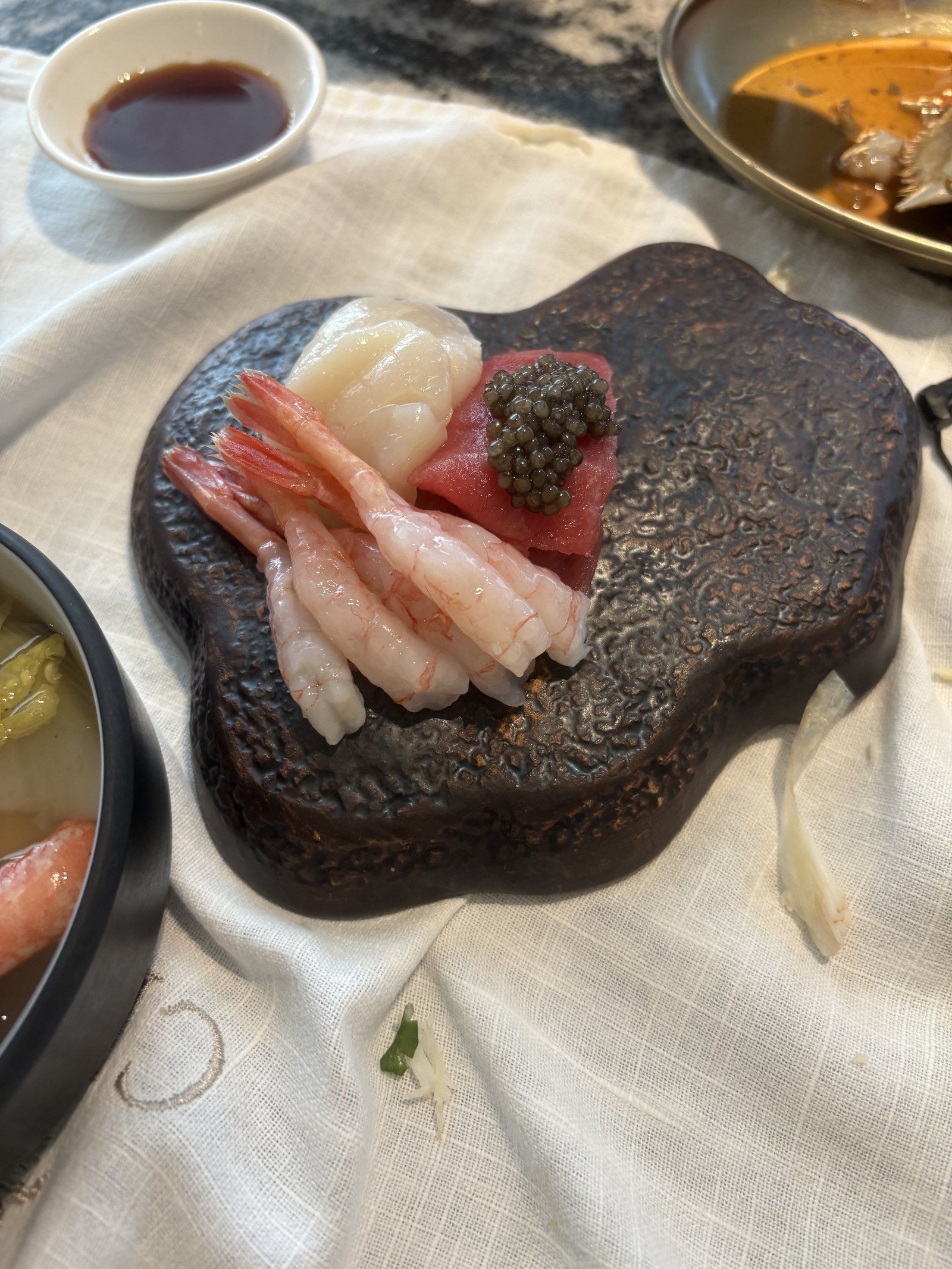 Sashimi plated on dark stone at Crab 52 Seoul, from the order menu