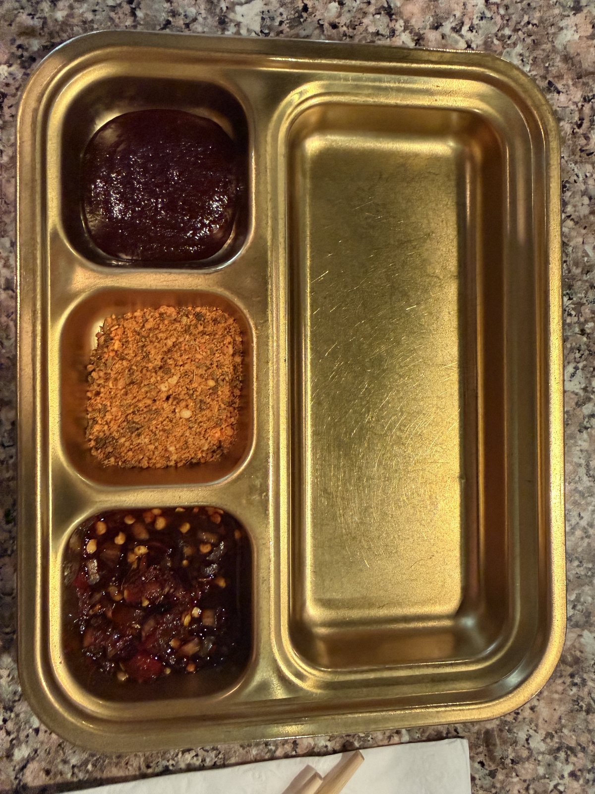 Metal tray of cumin, chili powder and chili oil for dipping skewers at Fei Xiang Gong in Los Angeles Koreatown