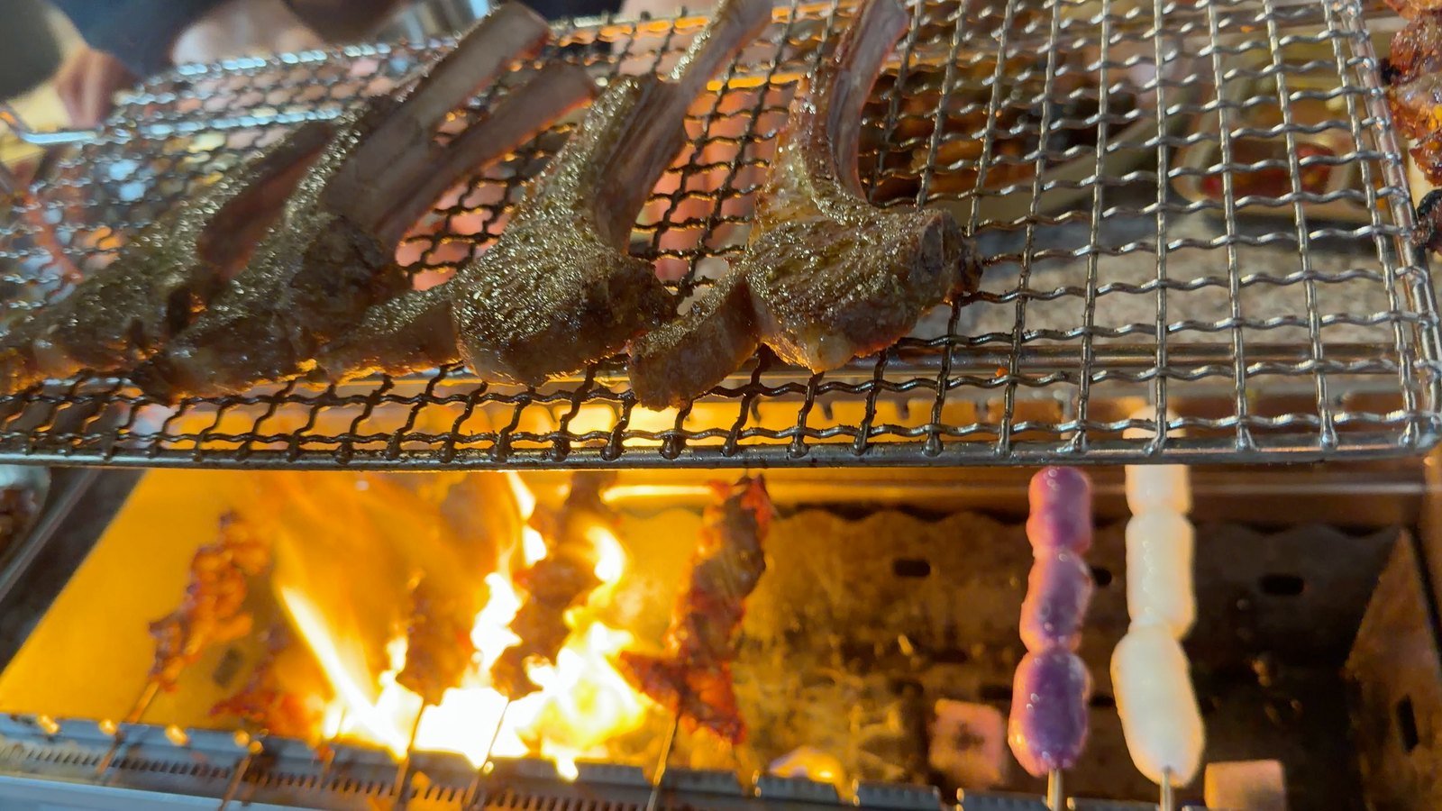 Bone-in lamb chops grilling over an open flame at Fei Xiang Gong in Los Angeles Koreatown