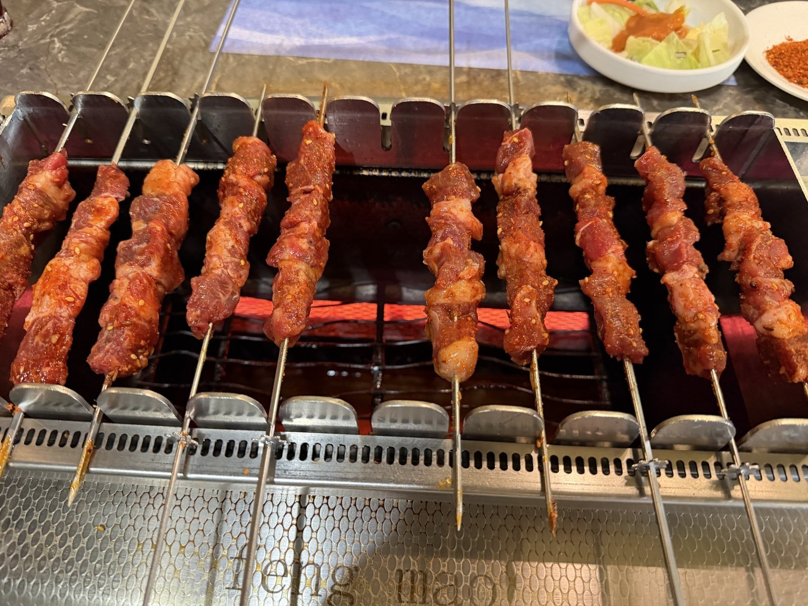 Lamb skewers cooking on the rotating grill at Feng Mao in Los Angeles Koreatown
