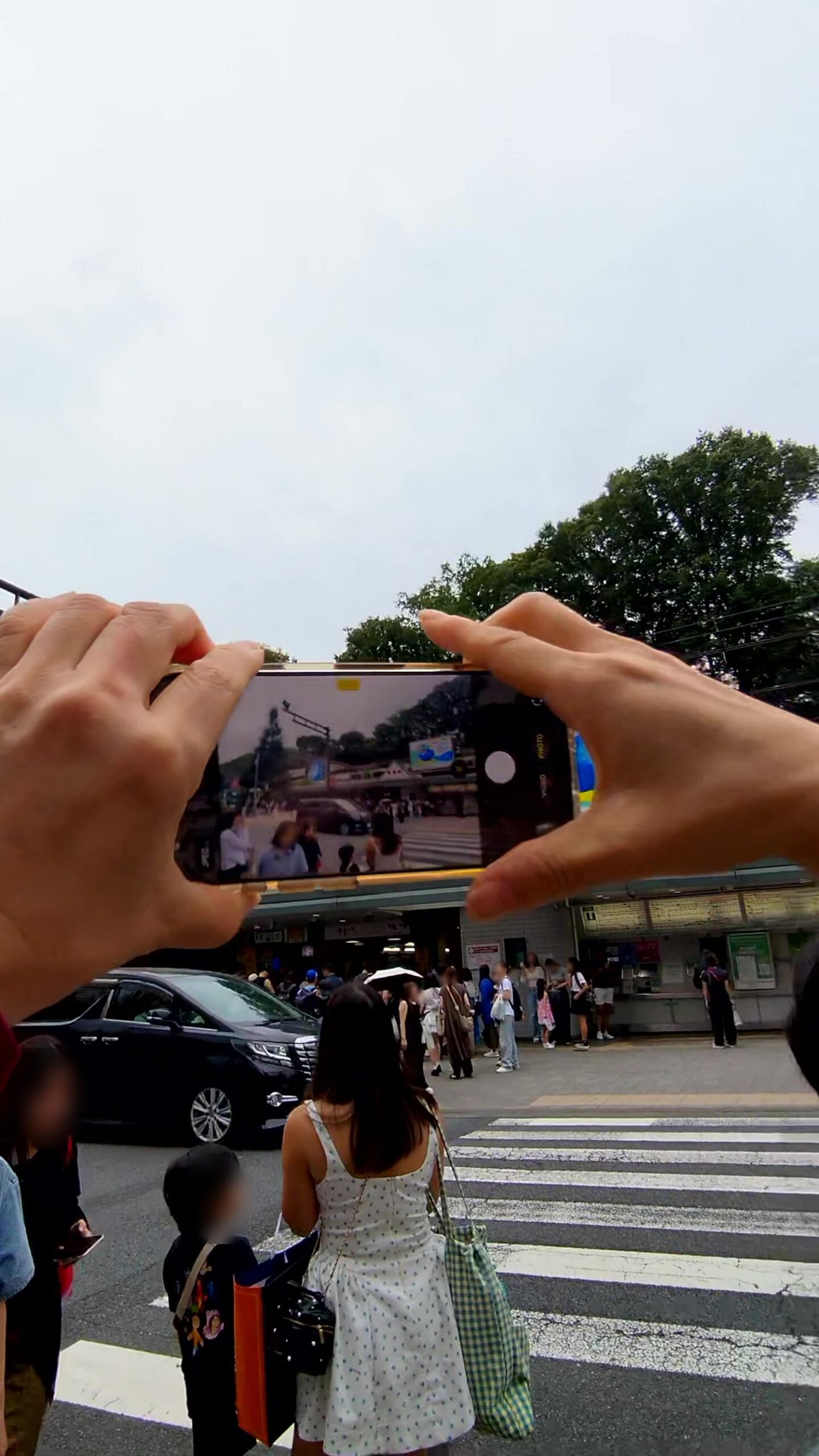 A visitor filming the crossing in front of Harajuku Station