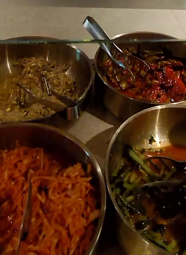 Steel bowls of Korean side dishes including seasoned bean sprouts and carrot namul at the Korean Air lounge buffet