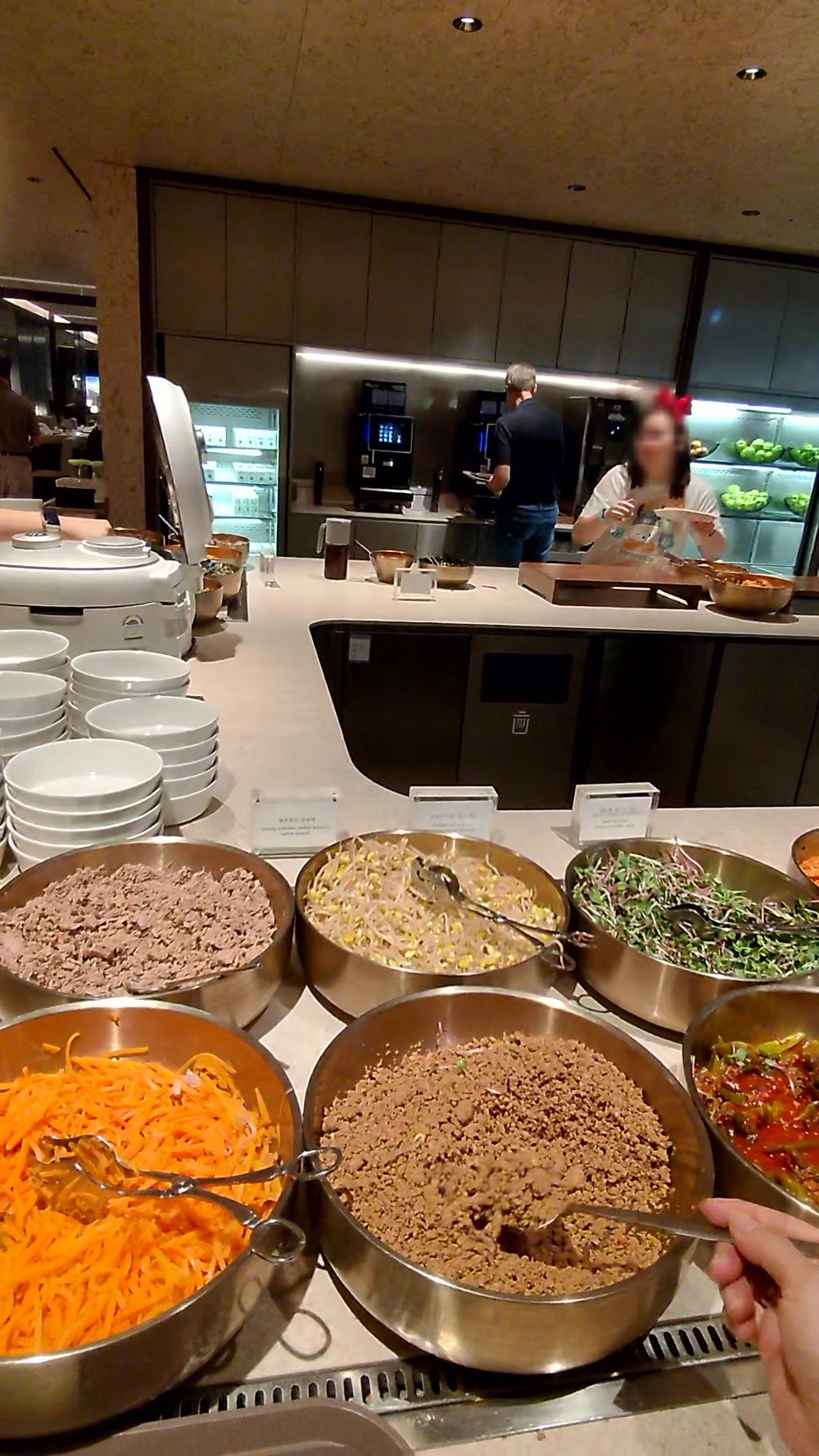 Brass bowls of Korean namul vegetables and minced beef at the bibimbap counter in the Korean Air lounge
