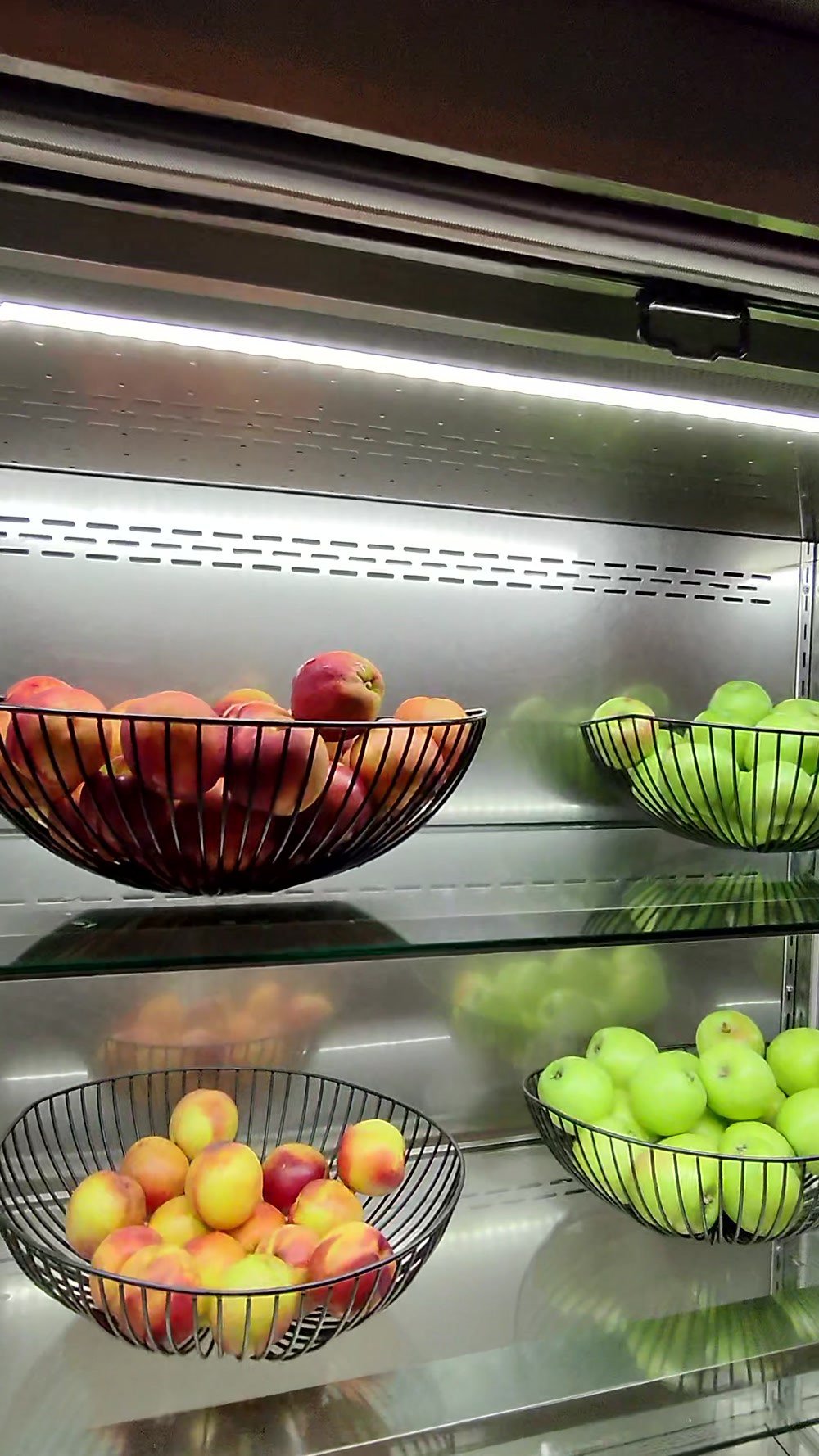 A lit fruit display cabinet with apples, pears and grapes at the Korean Air lounge at Incheon Airport