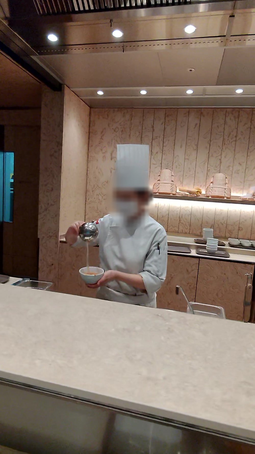 A chef ladling soup into a bowl at the Noodle Bar counter in the Korean Air lounge at Incheon