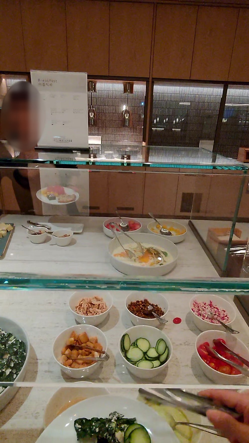 Banchan and namul bowls behind glass at the Korean Air lounge buffet at LAX