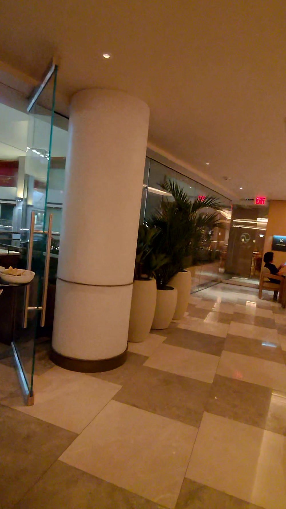 Seating area with tall planters and a lit column inside the Korean Air lounge at LAX