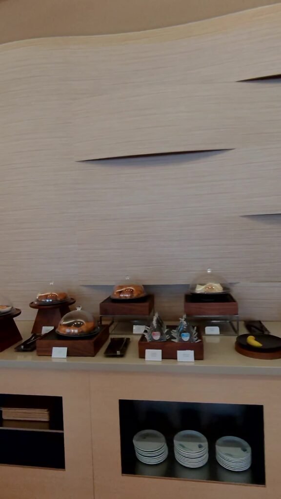 Buffet counter with covered chafing dishes and stacked plates at the Korean Air lounge in Narita