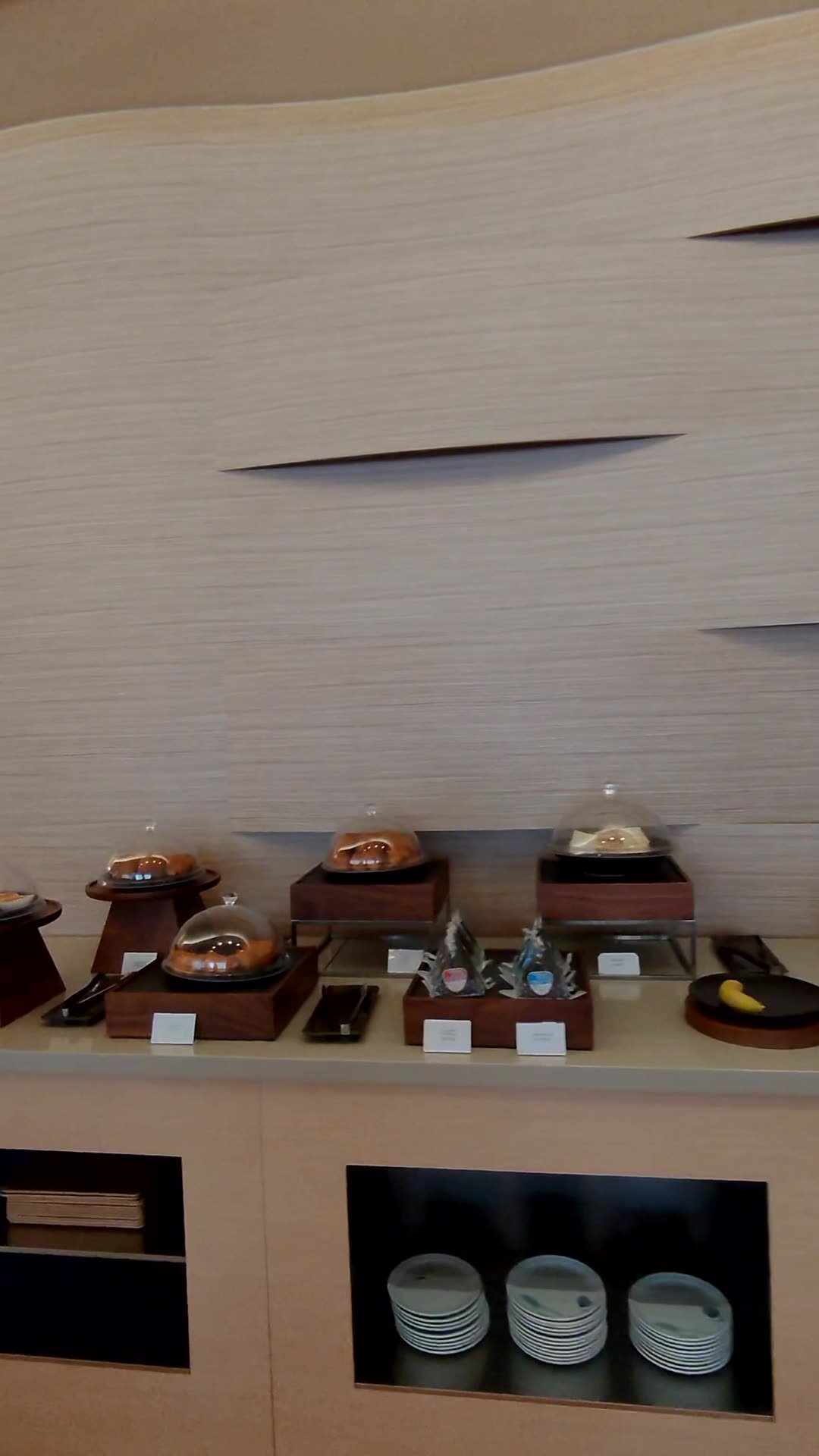 Buffet counter with covered chafing dishes and stacked plates at the Korean Air lounge in Narita