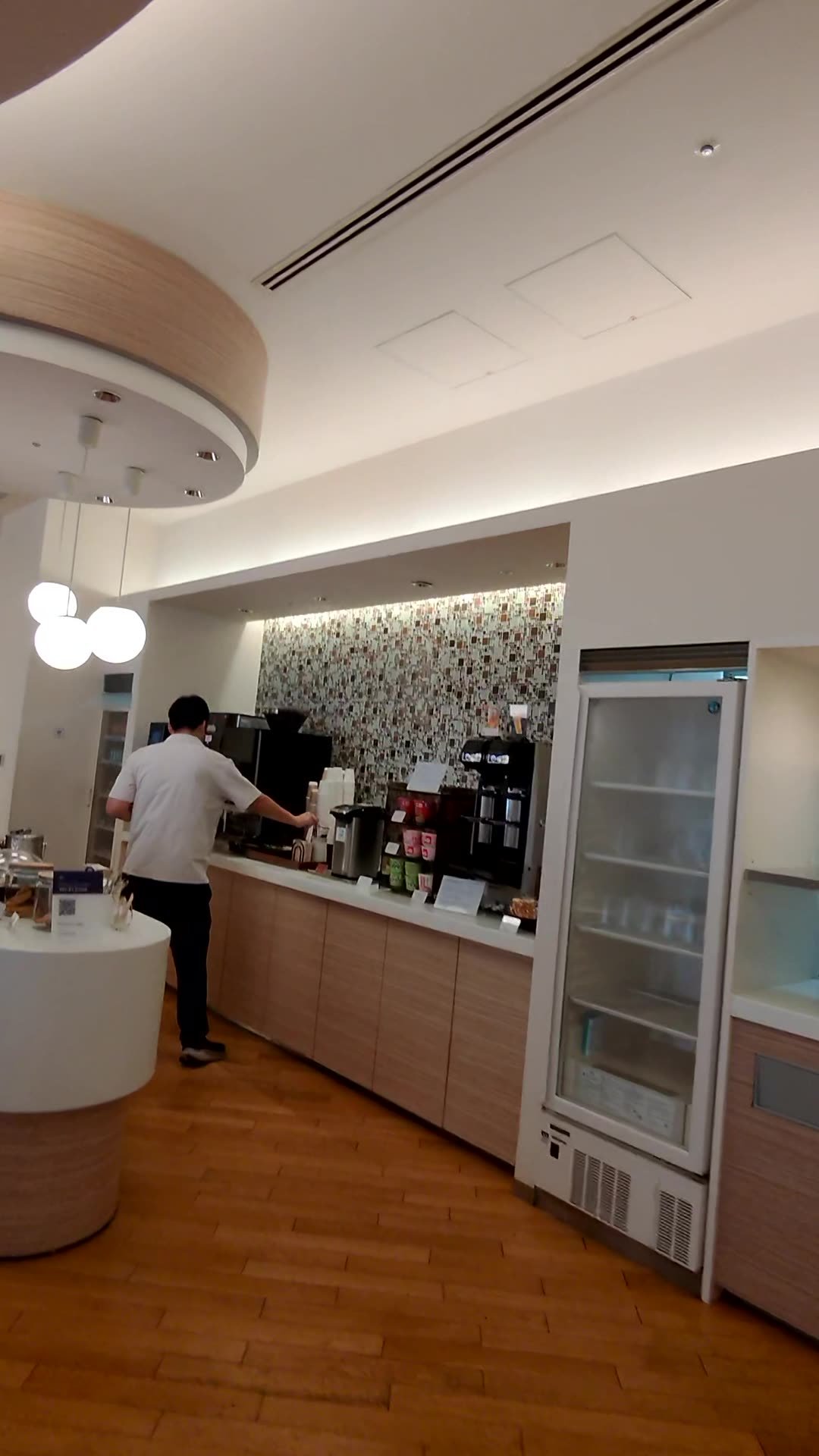 Self-serve coffee and drinks station with an espresso machine and glass-front fridge at the Korean Air lounge in Narita