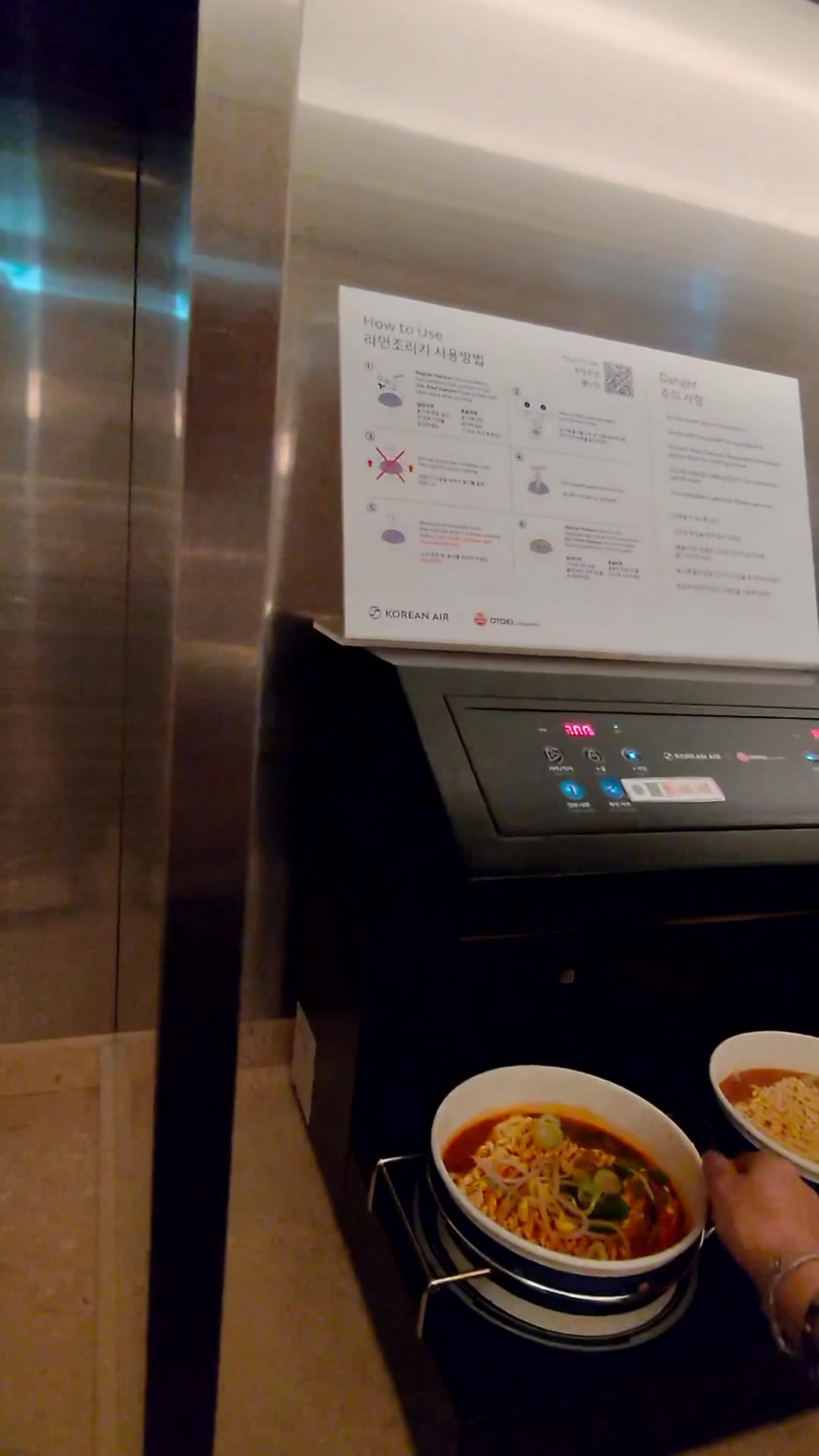 The automated ramen cooking machine with a touchscreen and instruction card at the Korean Air lounge in Incheon