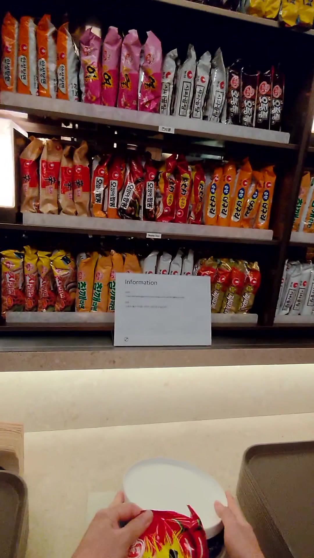 Shelves of Korean instant noodles and snacks beside the ramen station in the Korean Air lounge