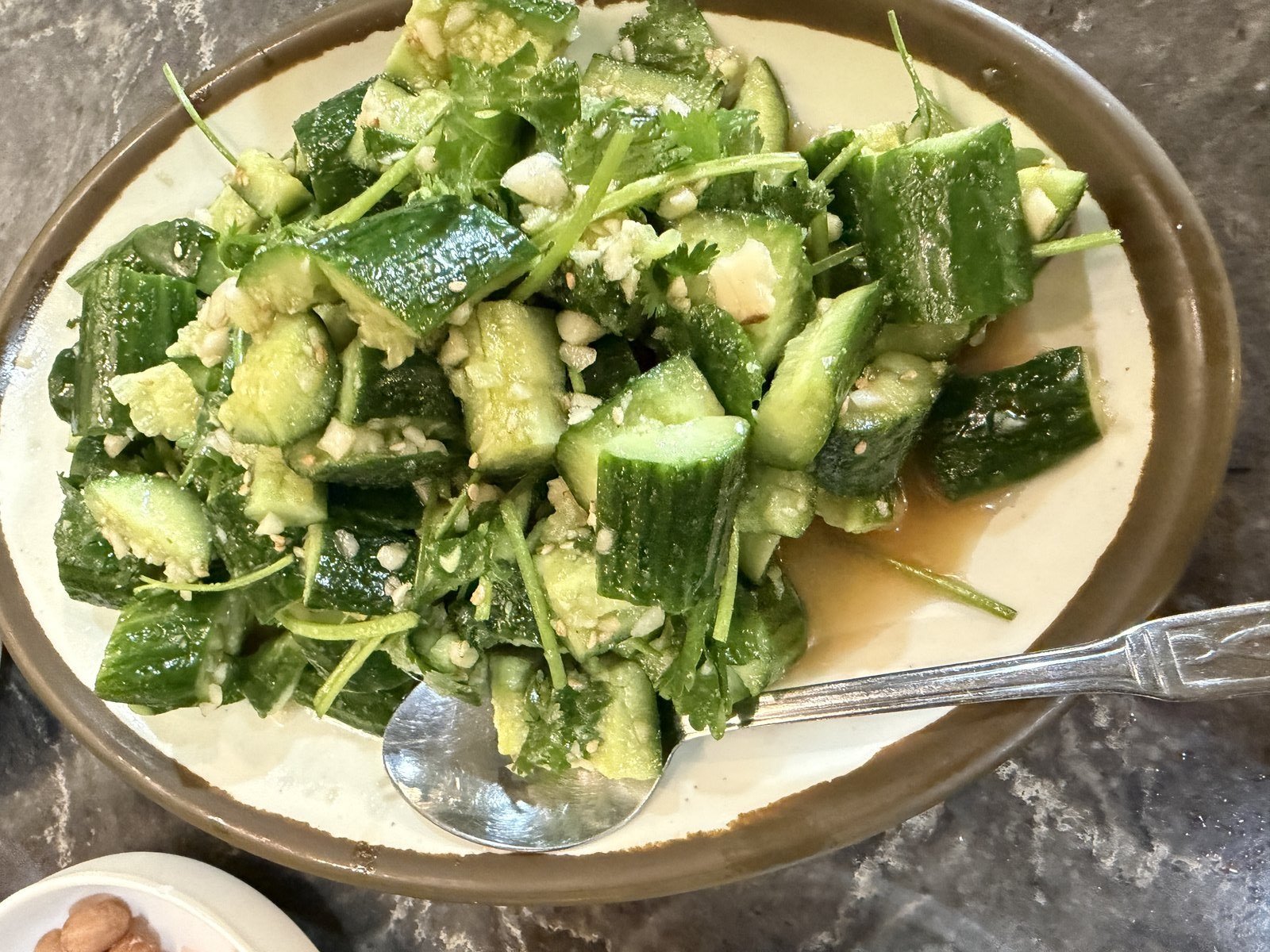 Plate of smashed cucumber salad with garlic and vinegar at a lamb skewer restaurant in Los Angeles Koreatown