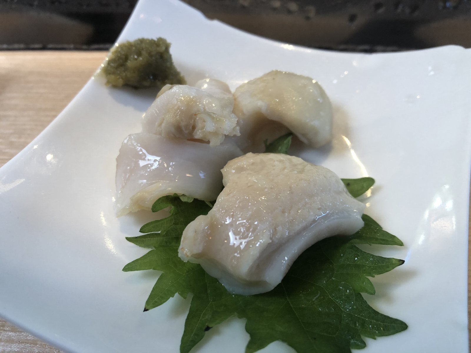Beverly Hills Sasabune shellfish sashimi served on a shiso leaf with wasabi