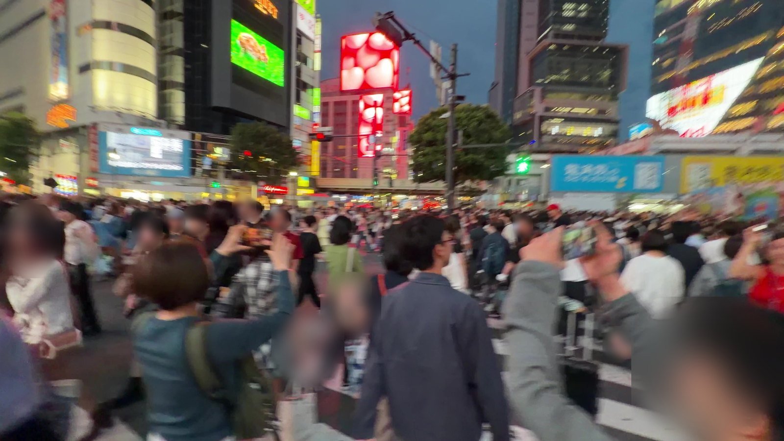 Visitors holding up phones to photograph Shibuya Crossing