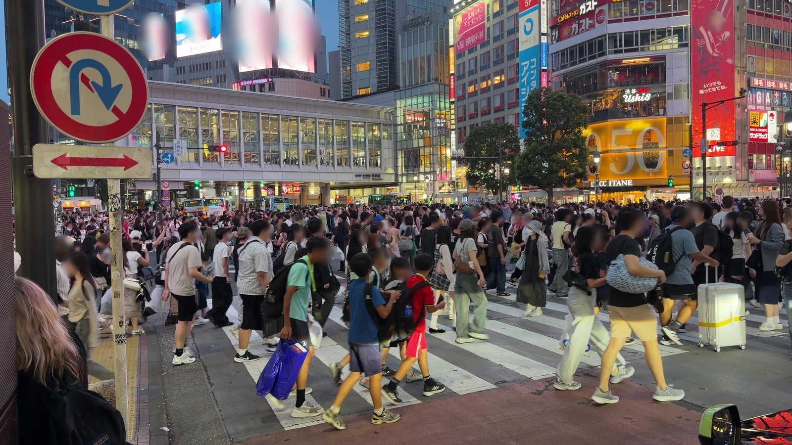 Travellers crossing Shibuya Crossing with suitcases