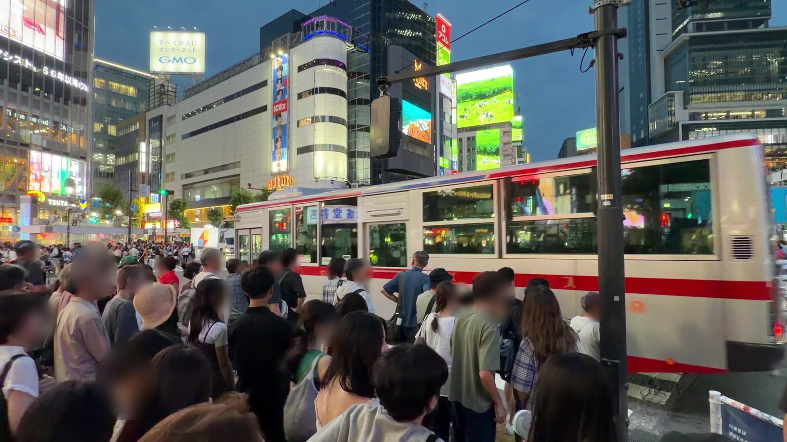 Crowd waiting at the corner of Shibuya Crossing as a bus passes