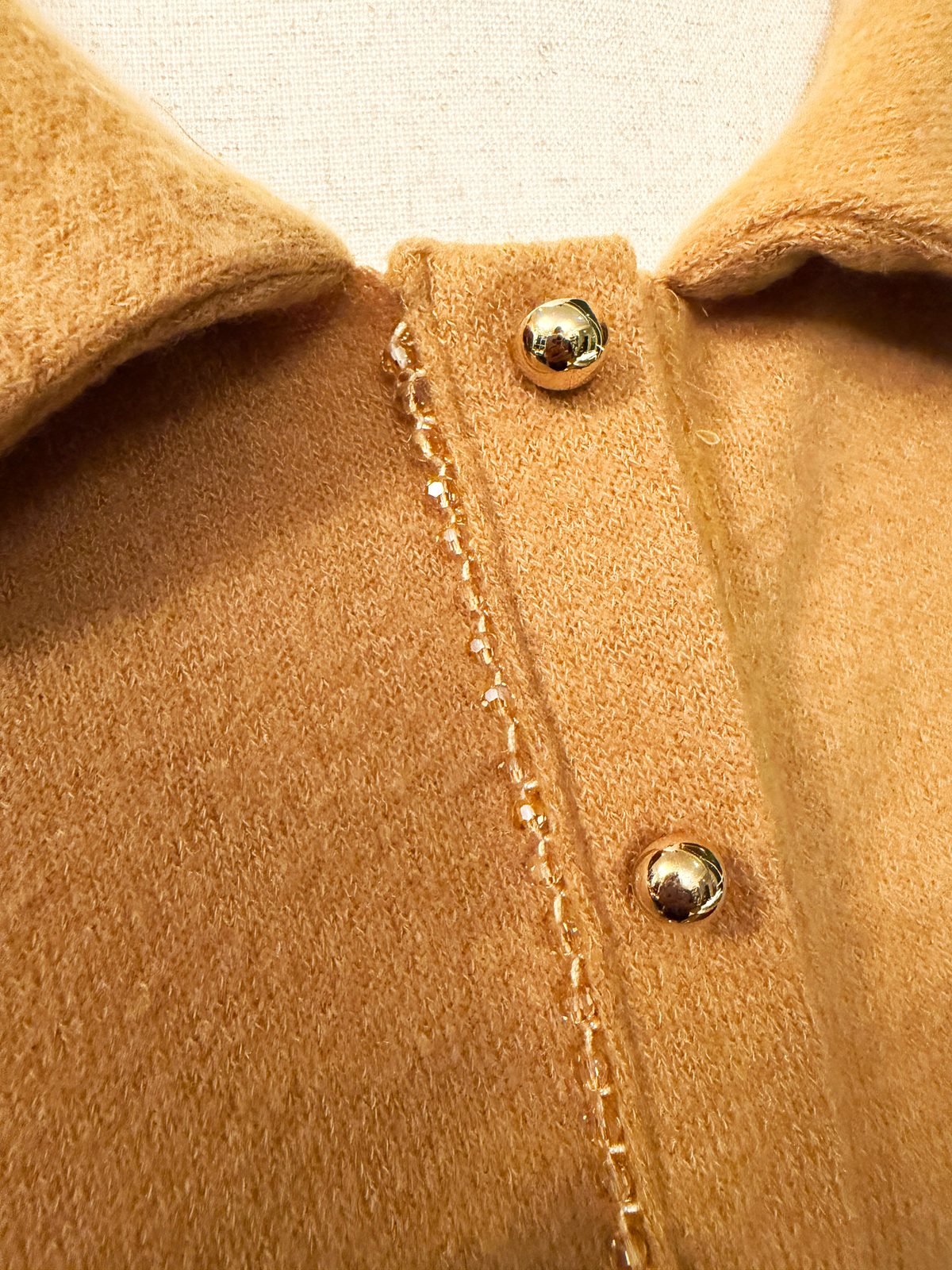 Close-up of beaded trim sewn beside the buttons on a handmade mustard knit dress