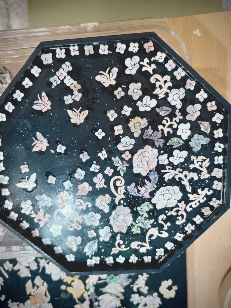 A small black lacquer tray covered edge to edge with mother-of-pearl flowers and butterflies